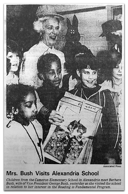 Photograph of a newspaper article covering Barbara Bush’s visit to Cameron Elementary. The article includes a picture of Bush with students. The photograph caption reads, Mrs. Bush Visits Alexandria School. Children from the Cameron Elementary School in Alexandria meet Barbara Bush, wife of Vice President George Bush, yesterday as she visited the school in relation to her interest in the Reading is Fundamental Program.