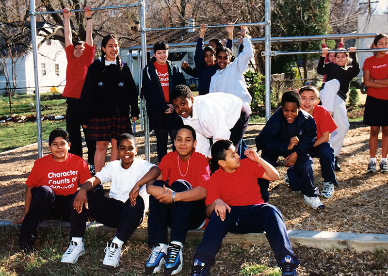 Color photograph of 15 students on the playground at Cameron Elementary School. They are wearing school uniforms.